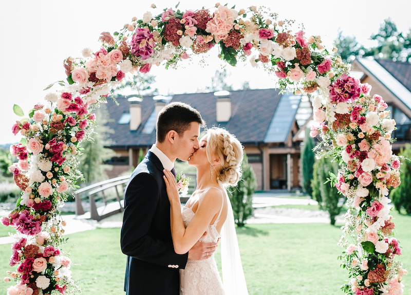Happy bride and groom kissing after wedding ceremony. couple newlyweds.Wedding ceremony under the arch decorated with flowers and greenery.