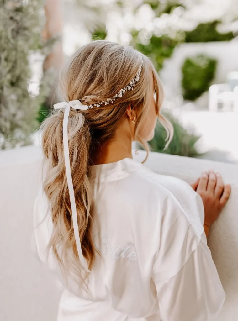 boho-curly-low-ponytail-wedding-hair-inspo-with-pearl-and-bow-hairpiece