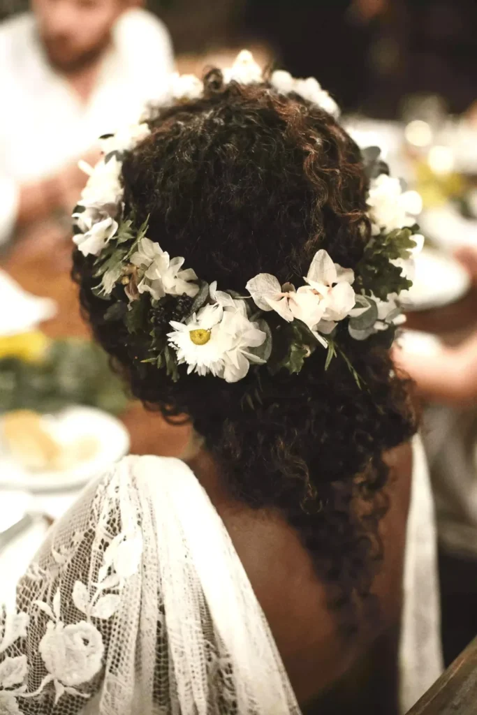 boho-low-bun-natural-curly-wedding-hair-inspo-with-floral-hairpiece